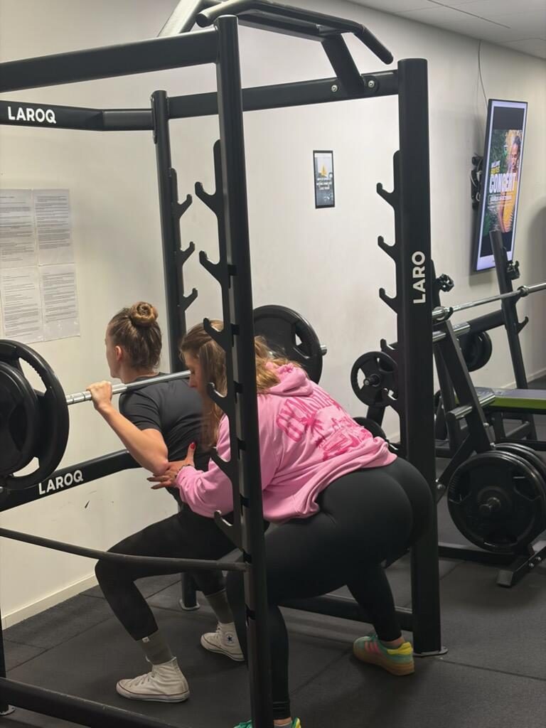Lara accompagne une cliente pendant la descente du squat