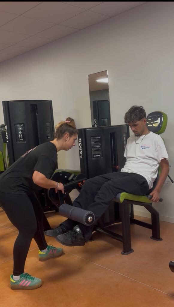 Lara guide un client sur une machine de musculation
